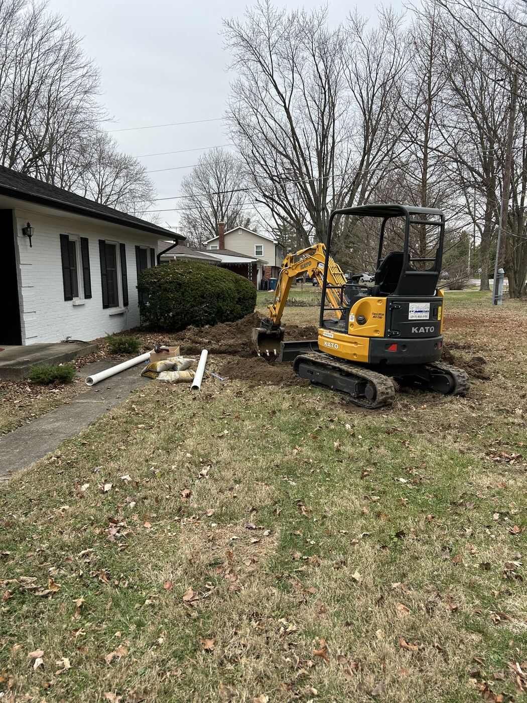 Mini excavator digging an exterior sewer line repair in an Indianapolis front yard